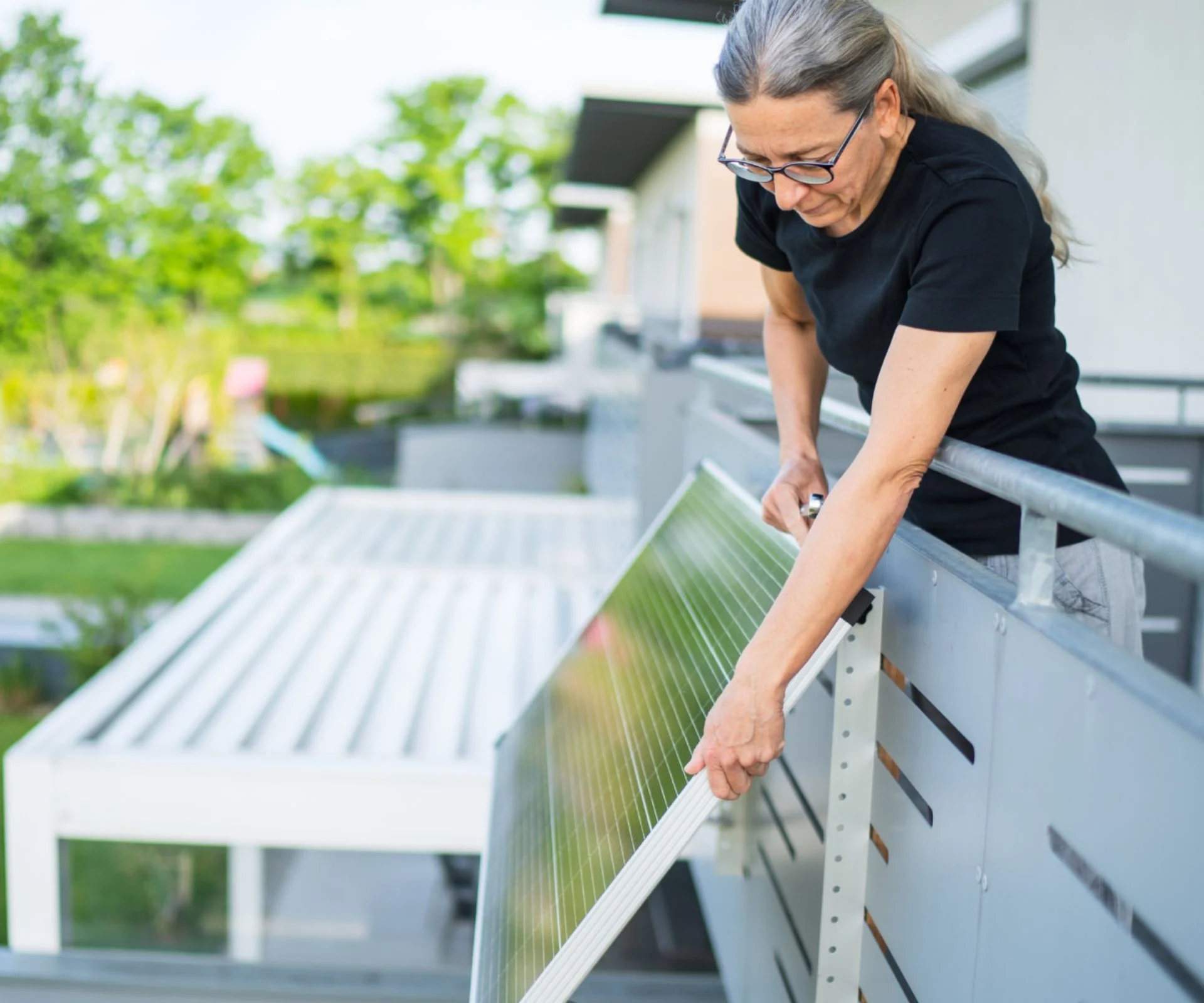 woman mounting plug-in solar panel on balcony