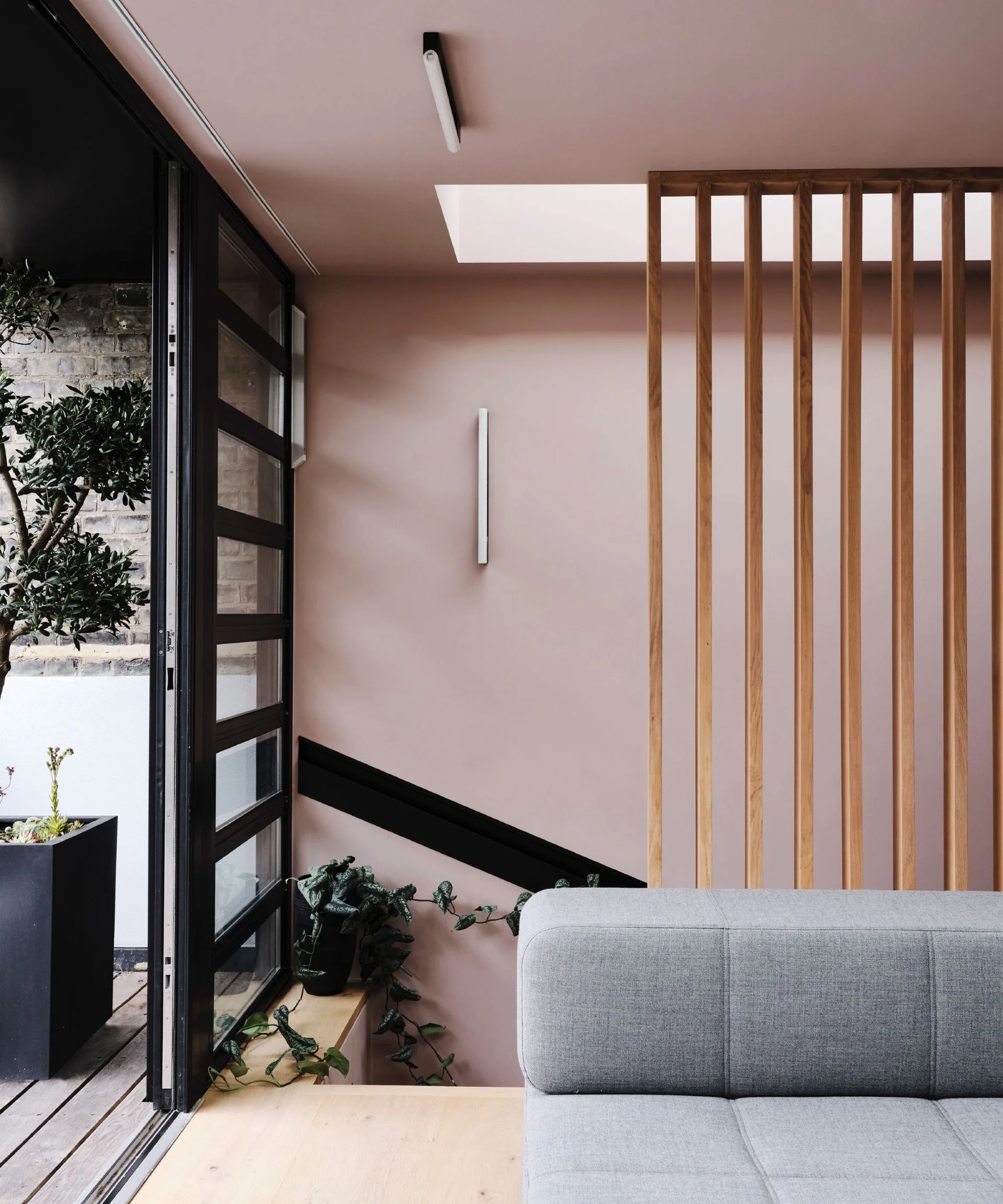 rose pink living room with gray modular couch, blond wood floor