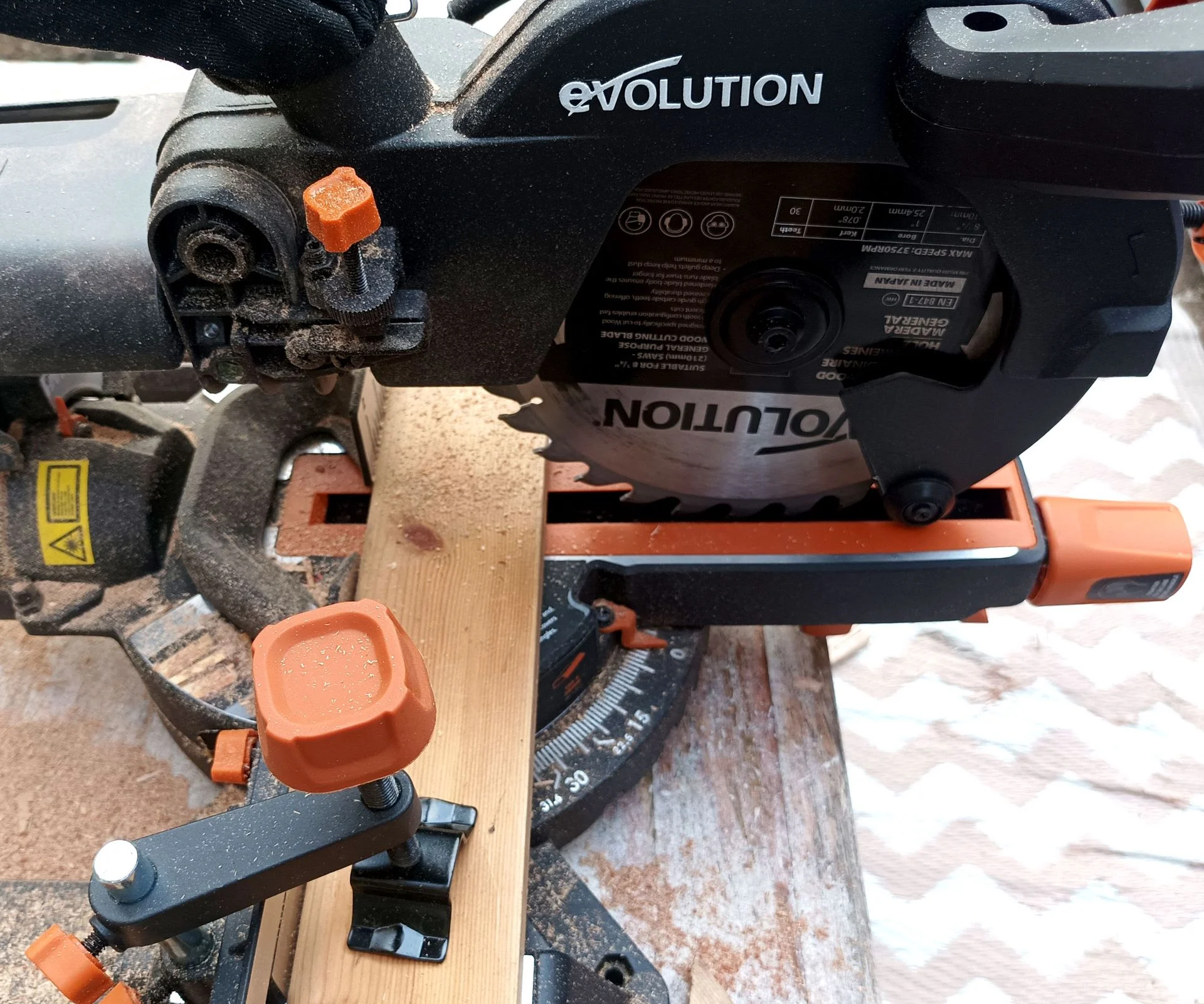 Close up of Evolution R210 SMS Plus mitre saw with skirting board clamped to saw