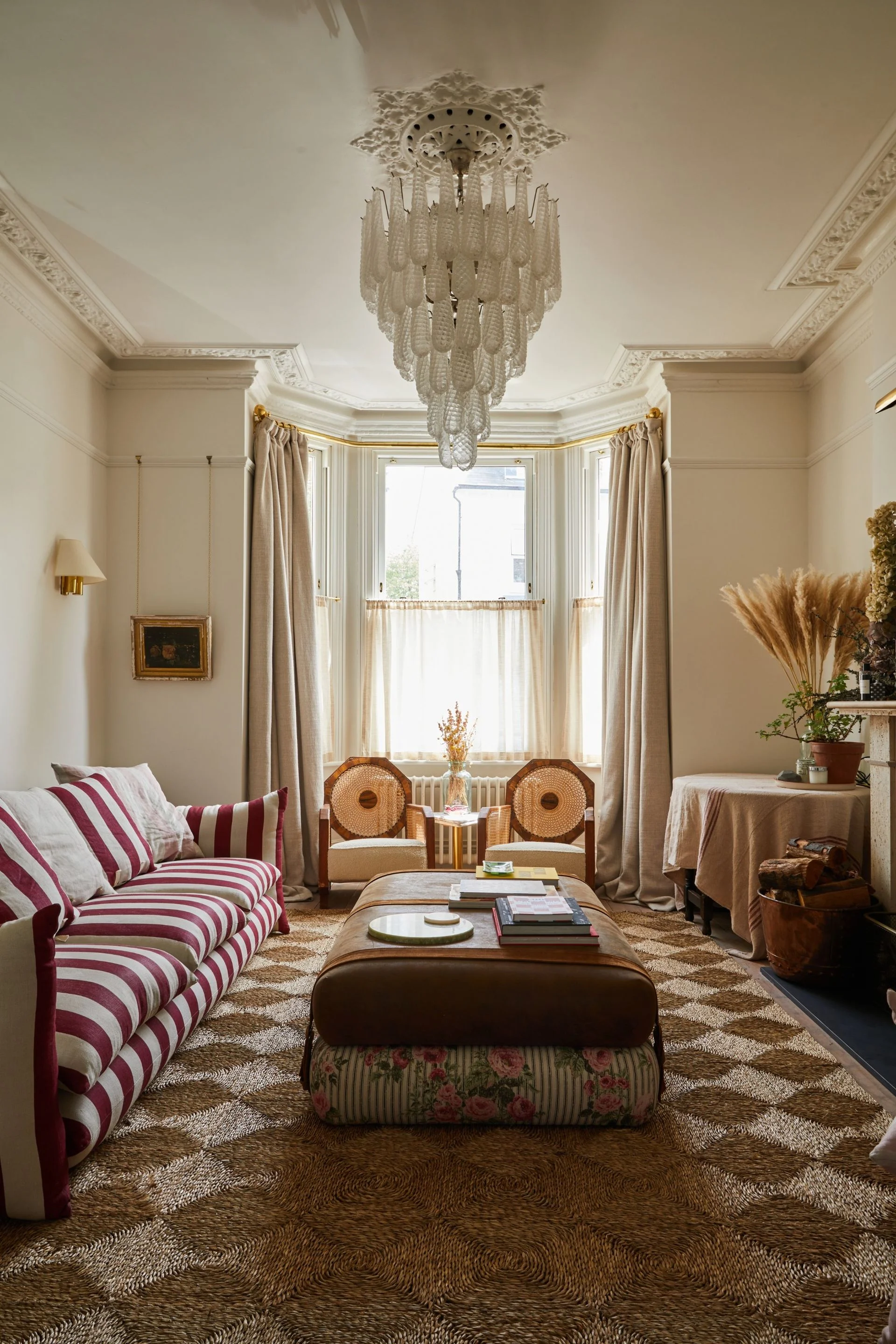 A lively living room with a striped sofa and chandelier.