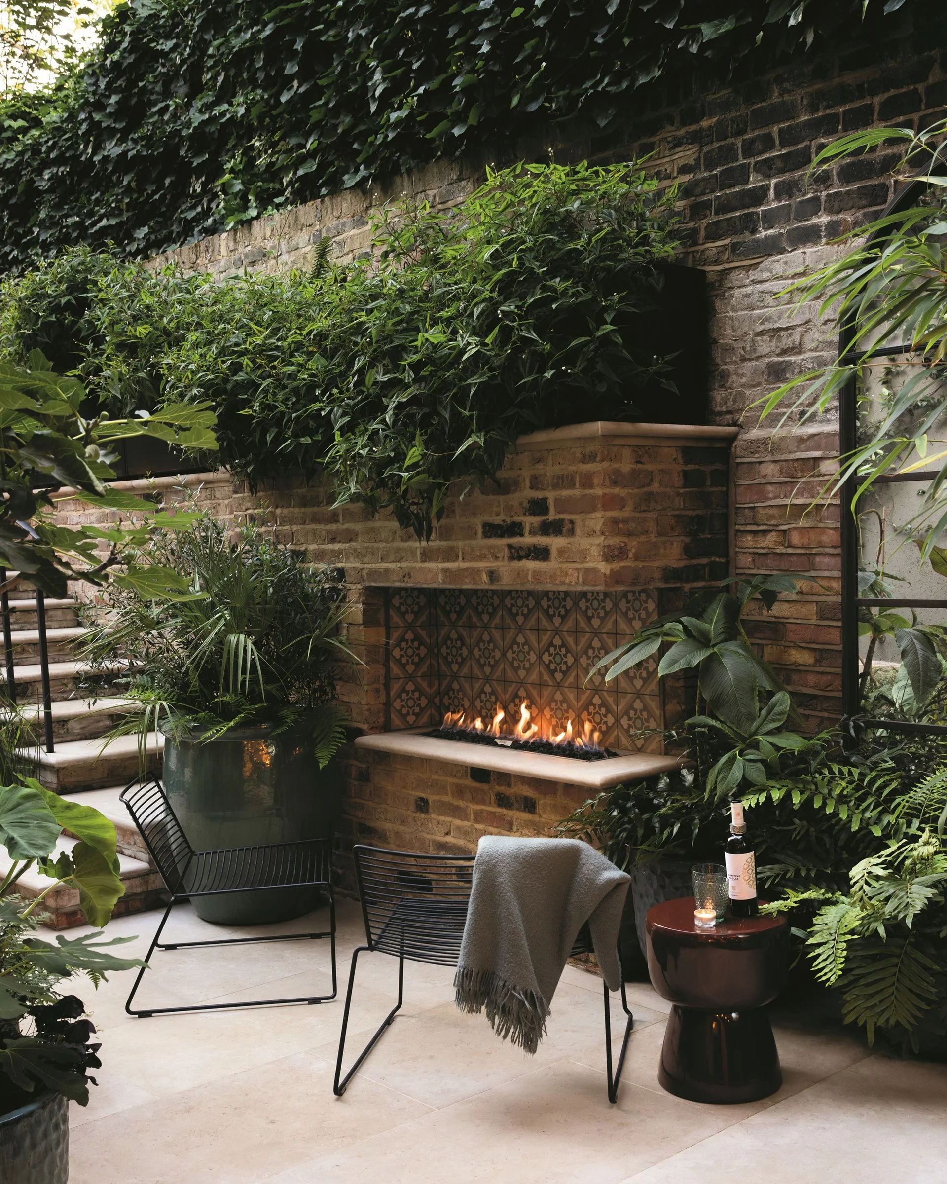 An outdoor fireplace built from brick in a verdant modern garden