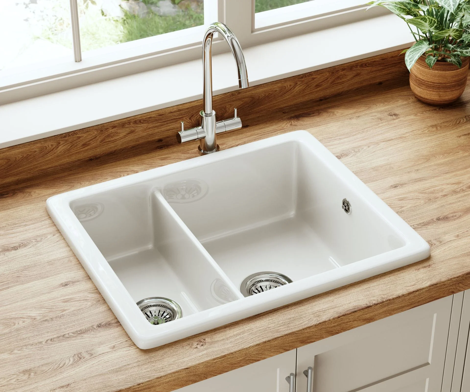 White ceramic double Belfast sink with chrome mixer tap on a wooden countertop by a window.