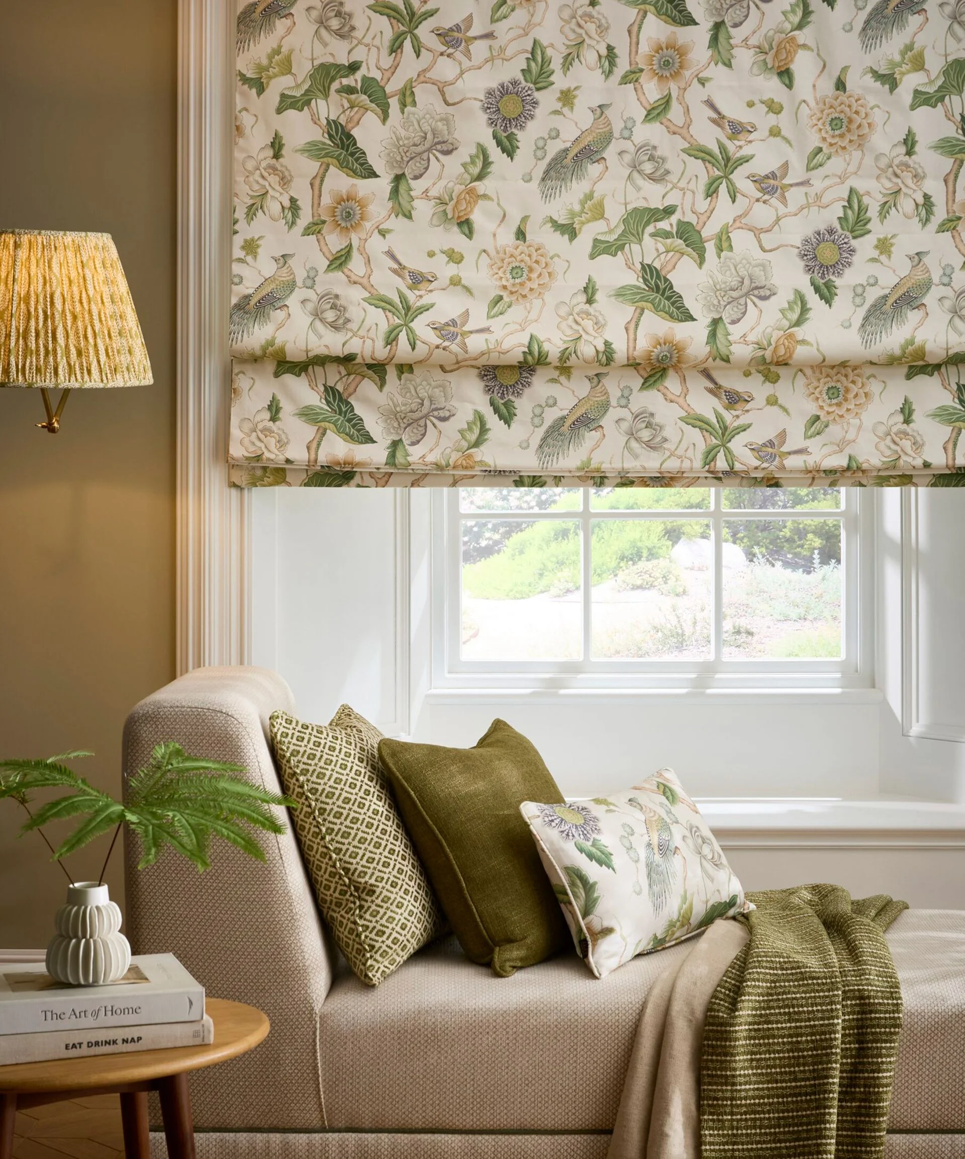 chaise longue in front of sash window with floral Roman blind