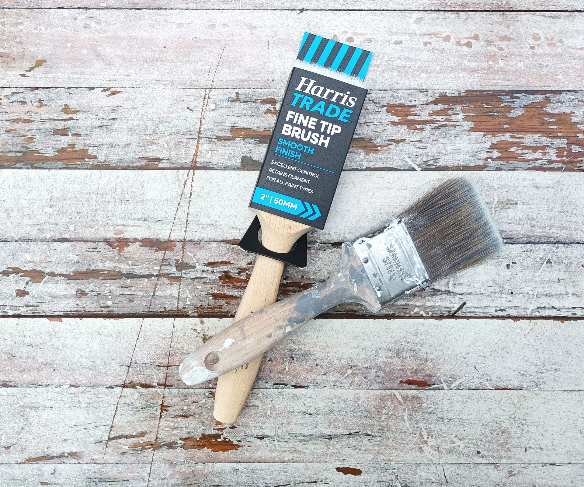 Two wooden two-inch paintbrushes on a whitewashed wood background