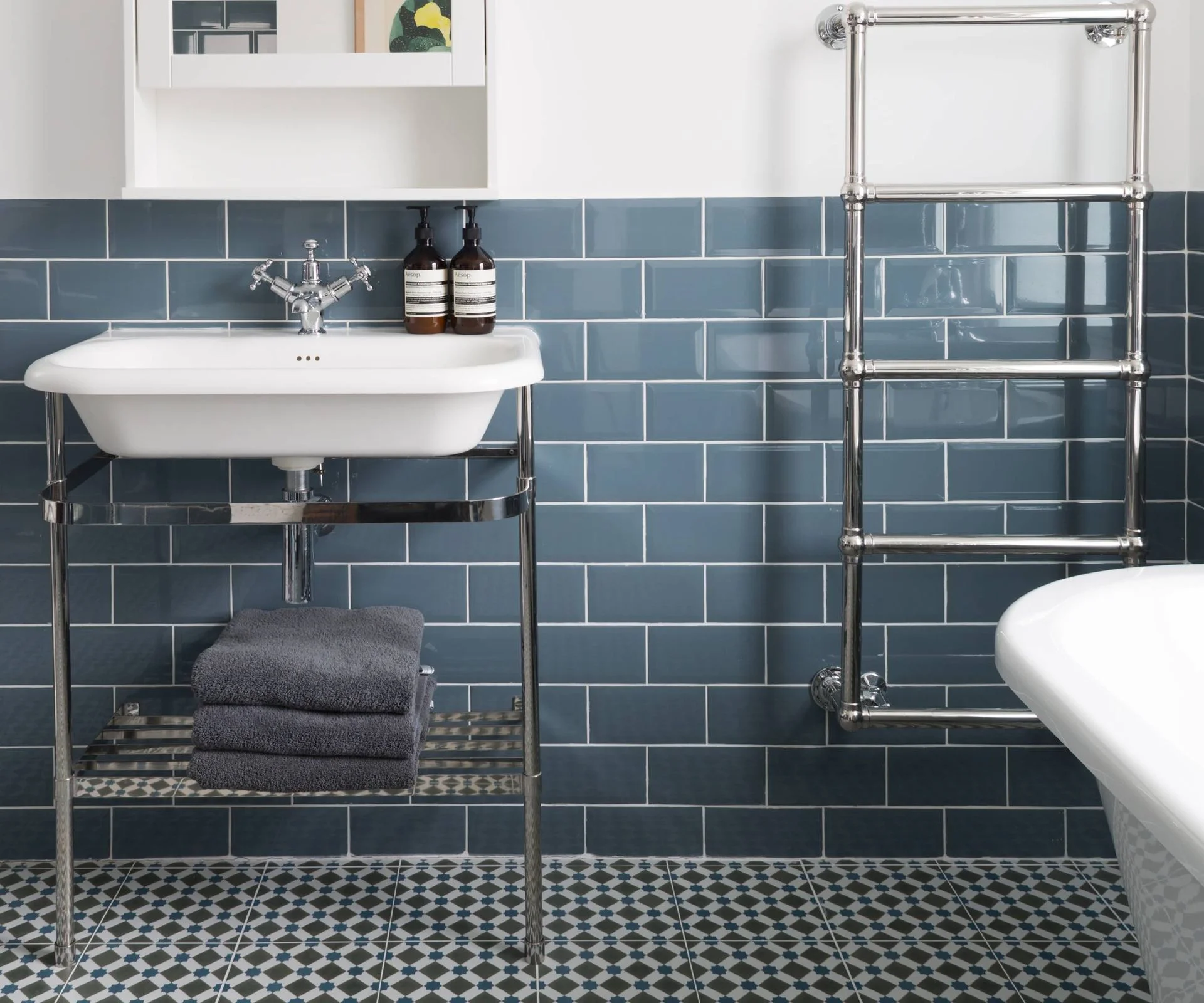 Blue tiled bathroom with vanity basin and towel rail