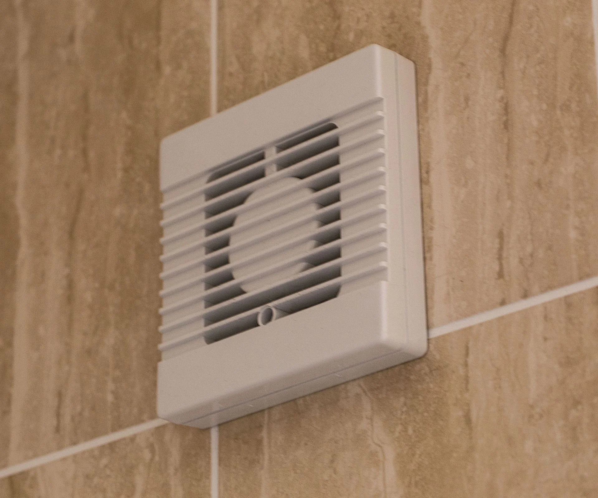 white bathroom extractor fan on beige wall tiles