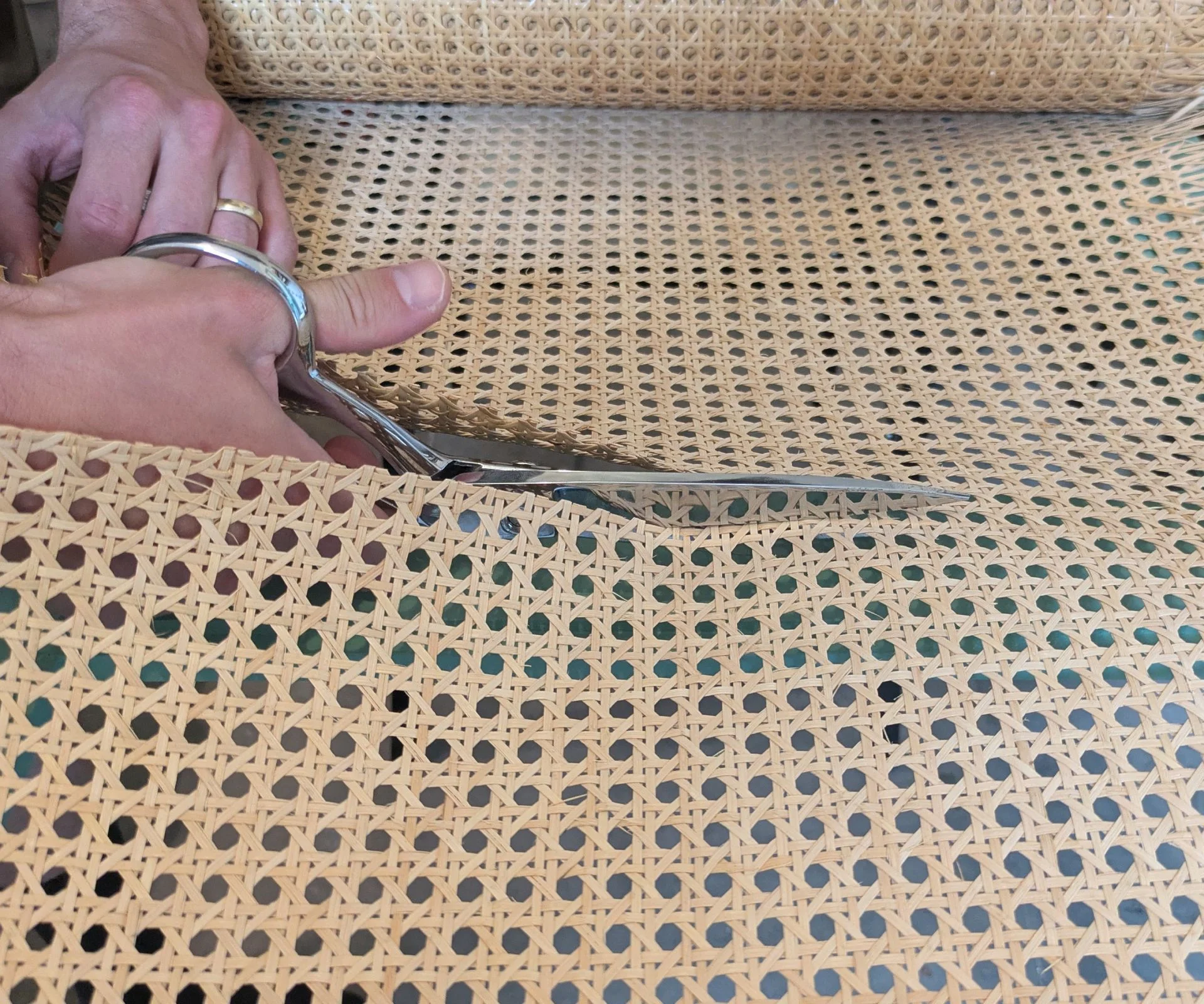 Scissors cutting through cane webbing