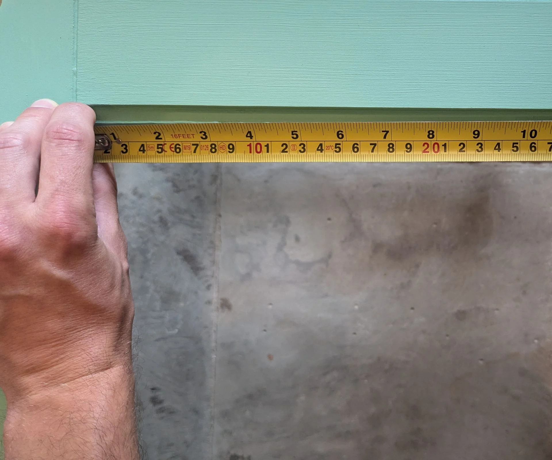 Using a tape measure to measure a wooden door section