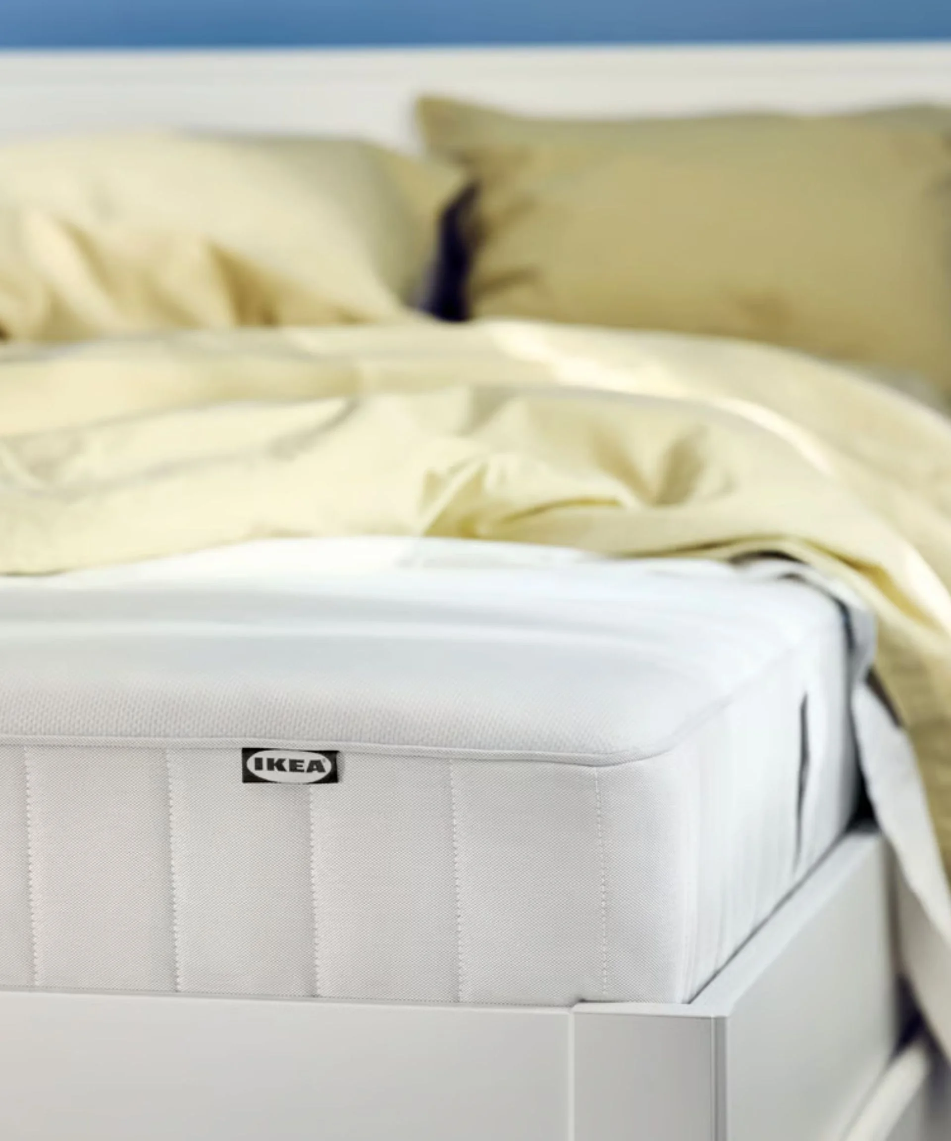 IKEA VESTERÖY Pocket spring mattress on a white bed with yellow bedding
