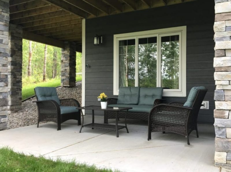 Dark-Themed Basement Patio with Wicker Chair and Coffee Table